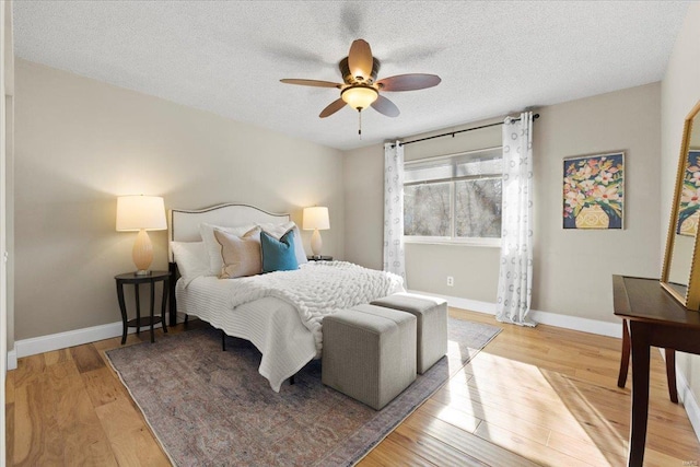 bedroom featuring baseboards, light wood-type flooring, and a textured ceiling