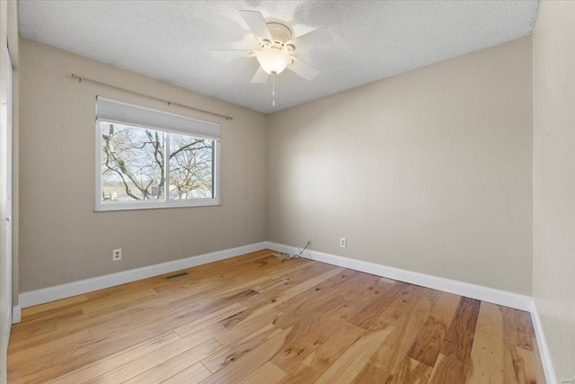 unfurnished room with visible vents, light wood-style flooring, a textured ceiling, and baseboards