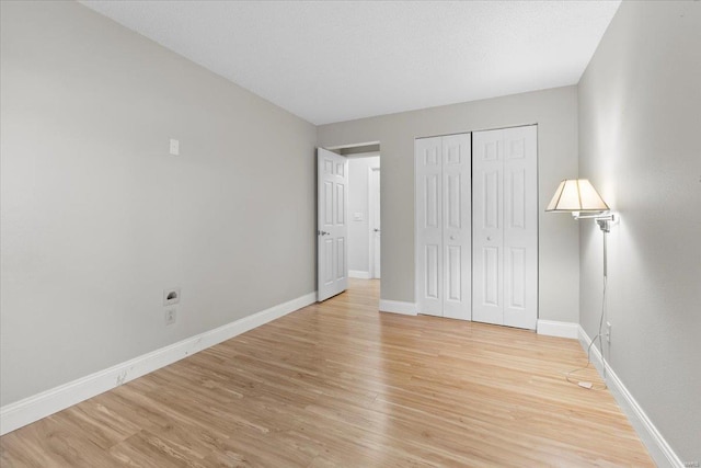 unfurnished bedroom with a closet, baseboards, and light wood finished floors