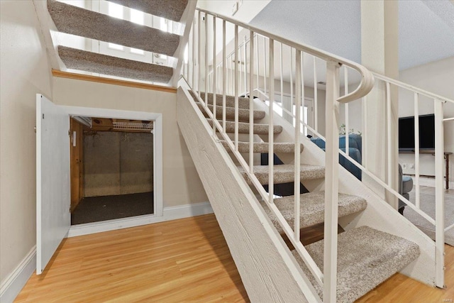 staircase with baseboards and wood finished floors