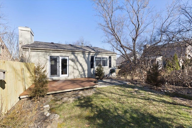 rear view of property featuring a deck, a lawn, fence, and a chimney