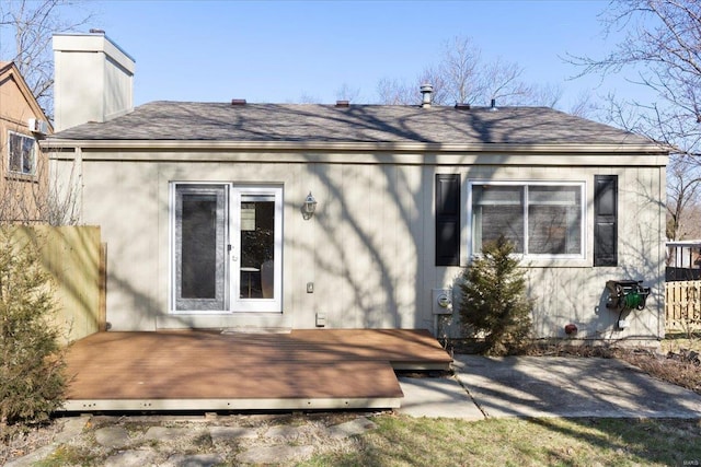 rear view of house featuring a chimney, a deck, and a shingled roof