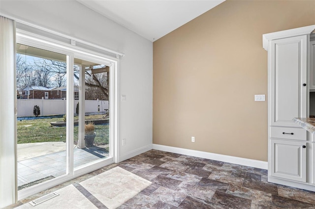 unfurnished room featuring stone finish floor, visible vents, and baseboards