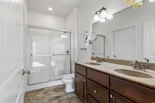 bathroom featuring double vanity, a stall shower, a sink, and toilet