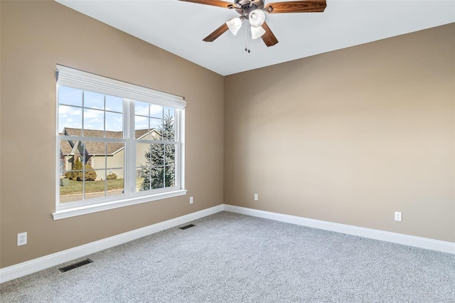 carpeted spare room featuring ceiling fan, visible vents, and baseboards