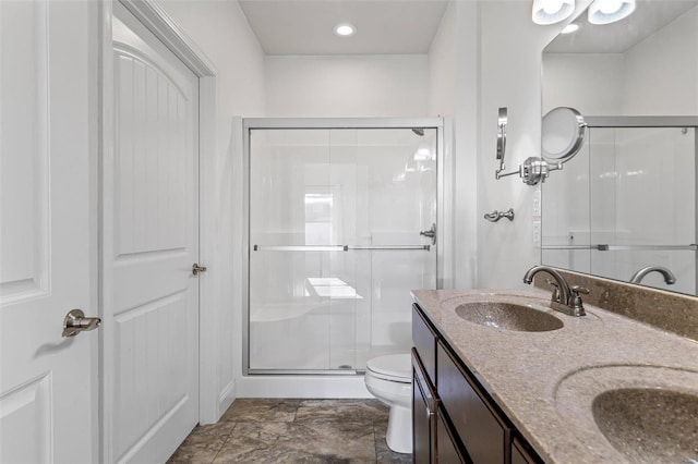 bathroom with a sink, a shower stall, toilet, and double vanity