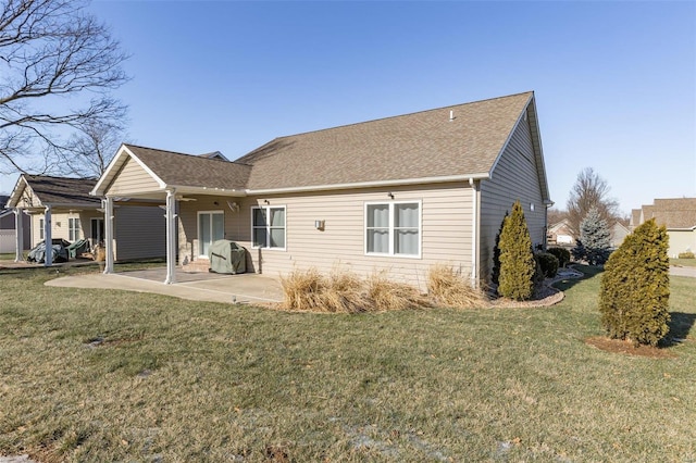 back of house with a yard, roof with shingles, and a patio area