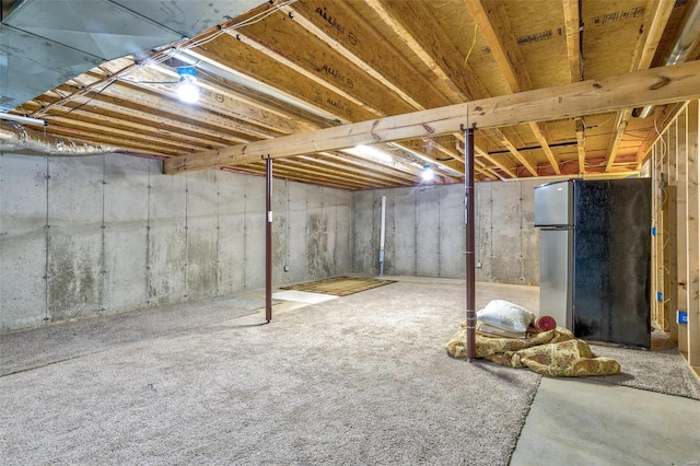 unfinished basement with freestanding refrigerator