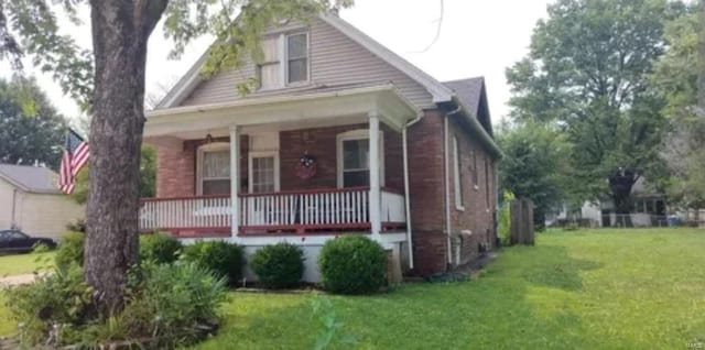 bungalow-style home featuring covered porch, a front lawn, and brick siding