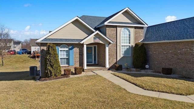 traditional home featuring a shingled roof, a front lawn, central AC, and brick siding