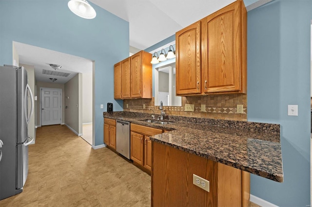 kitchen featuring stainless steel appliances, a sink, baseboards, decorative backsplash, and brown cabinetry