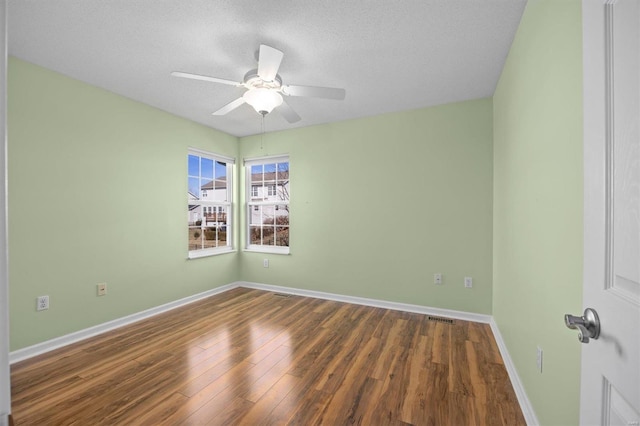 spare room featuring a textured ceiling, wood finished floors, a ceiling fan, visible vents, and baseboards