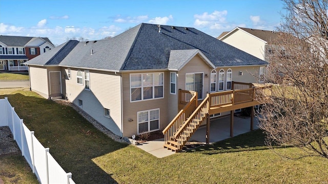 rear view of house with roof with shingles, a yard, stairway, fence, and a deck