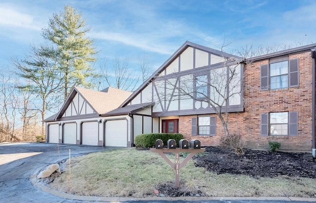 tudor home featuring a garage, brick siding, concrete driveway, stucco siding, and a front lawn