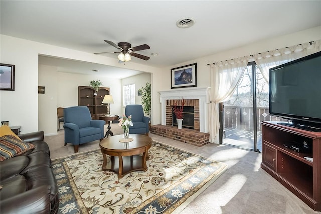 living room with a healthy amount of sunlight, a brick fireplace, visible vents, and light colored carpet