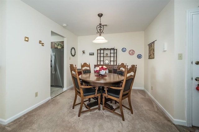 dining area featuring baseboards and light colored carpet