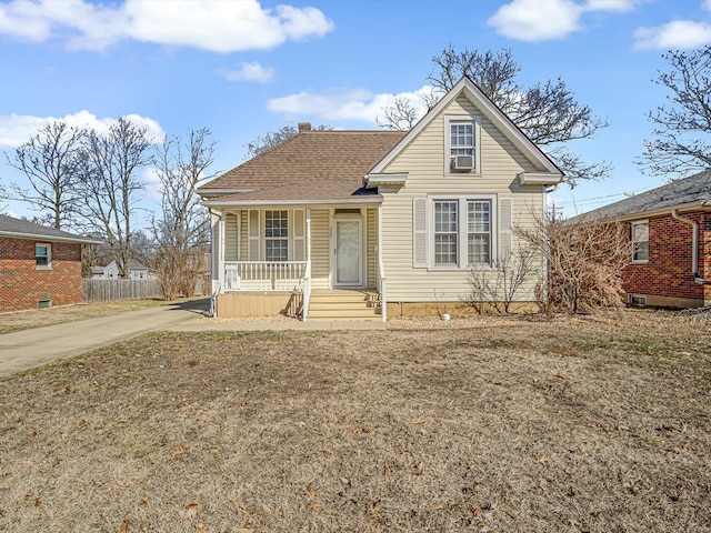 view of front of property with a porch, a shingled roof, and fence