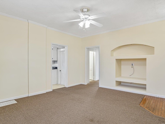 unfurnished living room featuring carpet floors, built in shelves, and crown molding