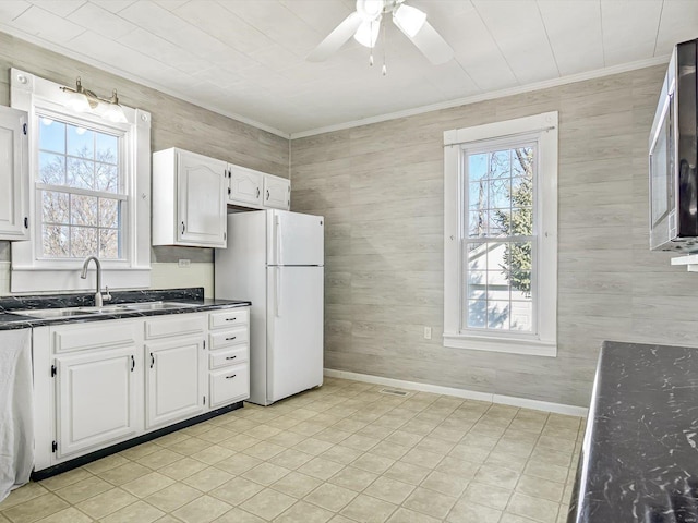 kitchen featuring freestanding refrigerator, white cabinets, a sink, and dark countertops