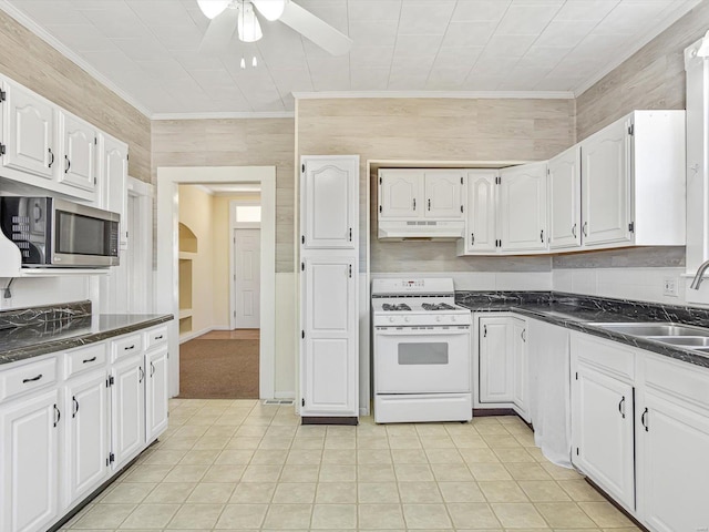 kitchen with white cabinets, stainless steel microwave, crown molding, under cabinet range hood, and gas range gas stove