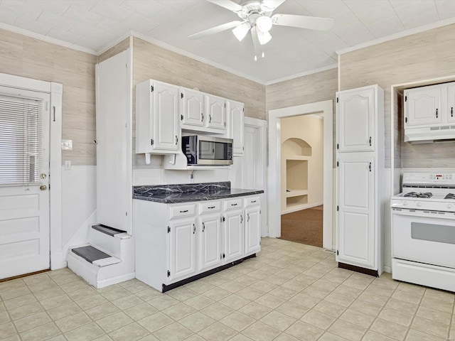 kitchen featuring white gas range oven, stainless steel microwave, crown molding, under cabinet range hood, and white cabinetry