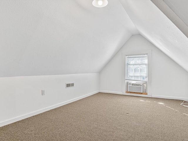 additional living space featuring cooling unit, carpet floors, visible vents, baseboards, and vaulted ceiling