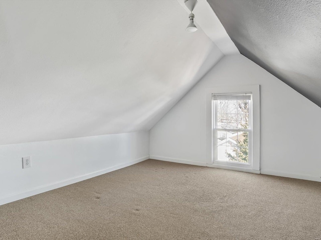 bonus room featuring carpet, baseboards, vaulted ceiling, and a textured ceiling