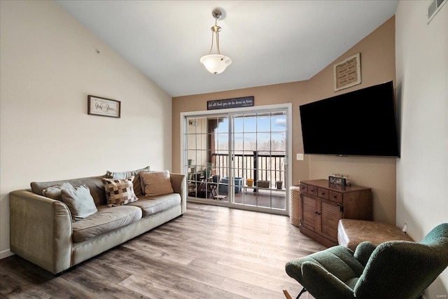 living room featuring visible vents, wood finished floors, and vaulted ceiling