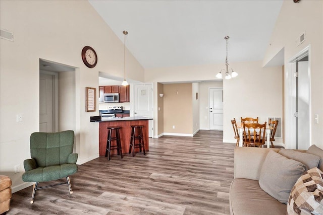 living area featuring dark wood-style floors, a notable chandelier, high vaulted ceiling, and visible vents