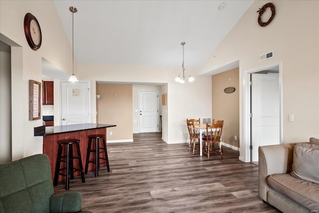 interior space featuring visible vents, baseboards, dark wood finished floors, an inviting chandelier, and high vaulted ceiling