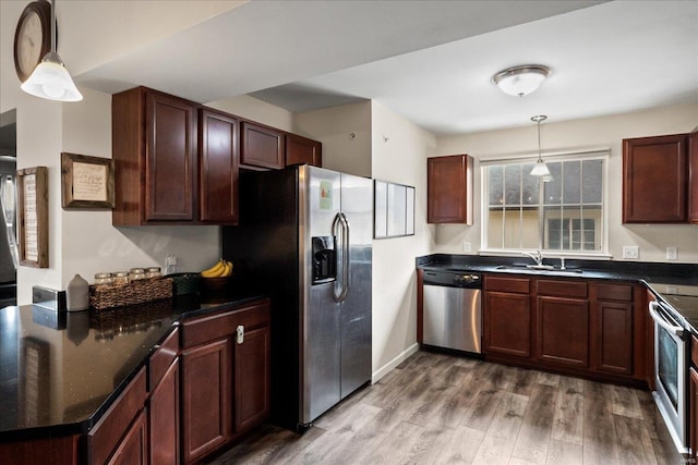 kitchen featuring a sink, decorative light fixtures, wood finished floors, stainless steel appliances, and baseboards