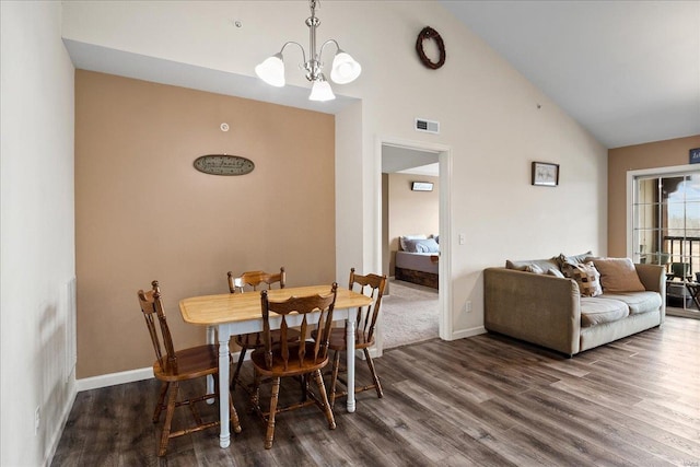 dining room featuring visible vents, baseboards, an inviting chandelier, wood finished floors, and high vaulted ceiling