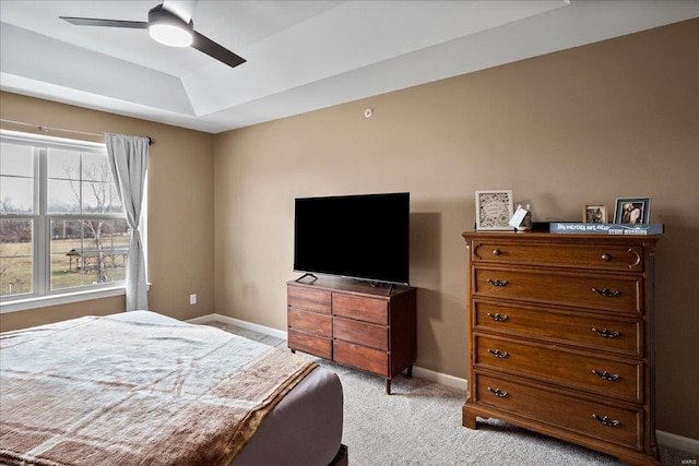 bedroom with a tray ceiling, baseboards, light colored carpet, and a ceiling fan