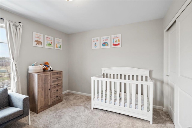 carpeted bedroom featuring a closet, baseboards, and a nursery area