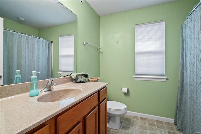 full bath with vanity, toilet, baseboards, and a wealth of natural light