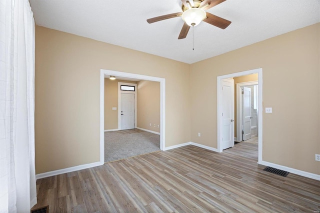 empty room featuring wood finished floors, visible vents, and baseboards