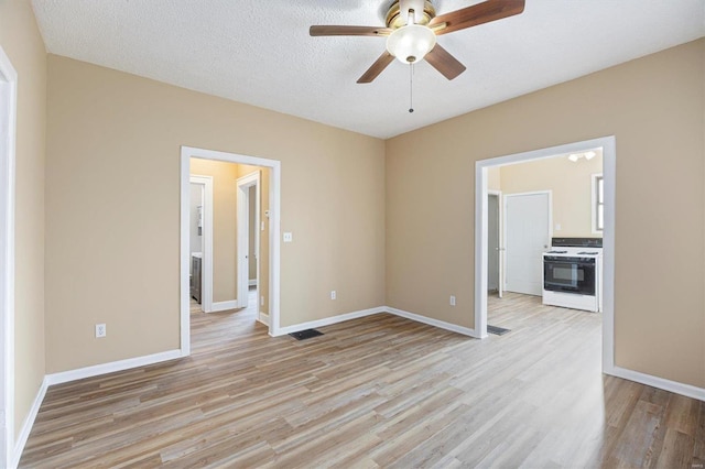 spare room with light wood-type flooring, visible vents, and baseboards