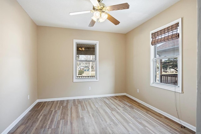 spare room with a healthy amount of sunlight, baseboards, and wood finished floors