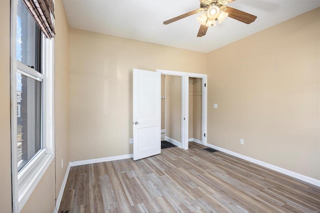 spare room featuring ceiling fan, light wood-style flooring, and baseboards