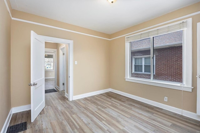 unfurnished room with wood finished floors, visible vents, and baseboards