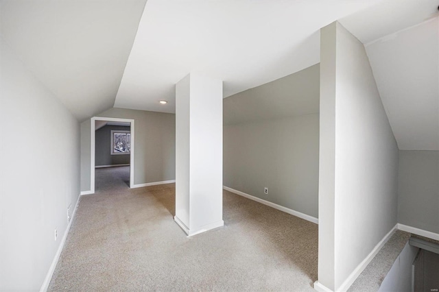 additional living space featuring carpet, baseboards, and vaulted ceiling