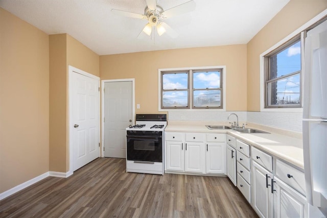 kitchen with a sink, a healthy amount of sunlight, white cabinets, light wood-style floors, and gas range oven