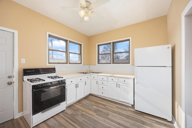 kitchen featuring light countertops, light wood-style flooring, white cabinetry, a sink, and white appliances