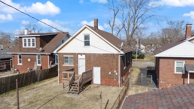 rear view of property with a chimney, fence, and brick siding