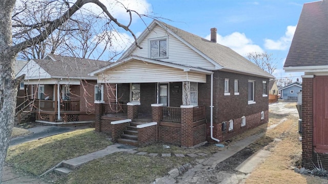 bungalow-style house featuring covered porch, brick siding, and crawl space