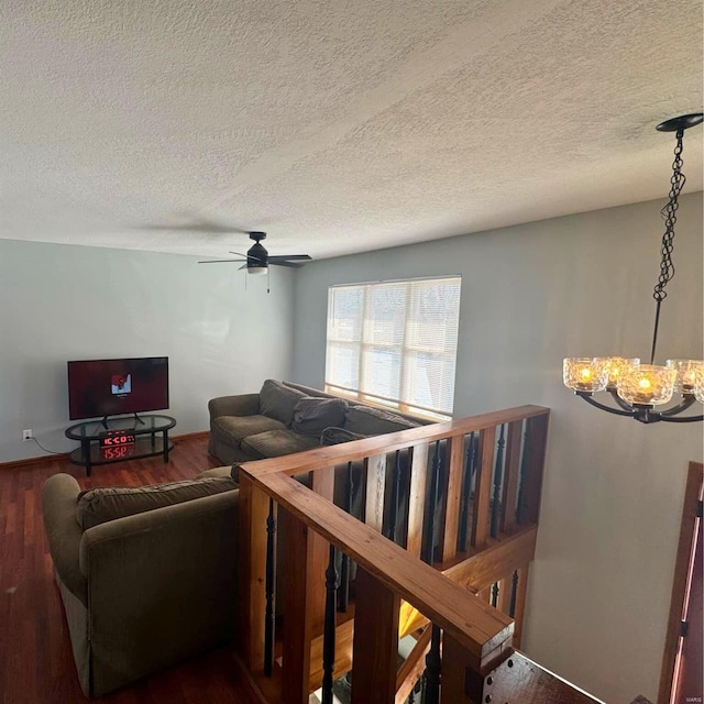 living room with ceiling fan with notable chandelier, a textured ceiling, and wood finished floors