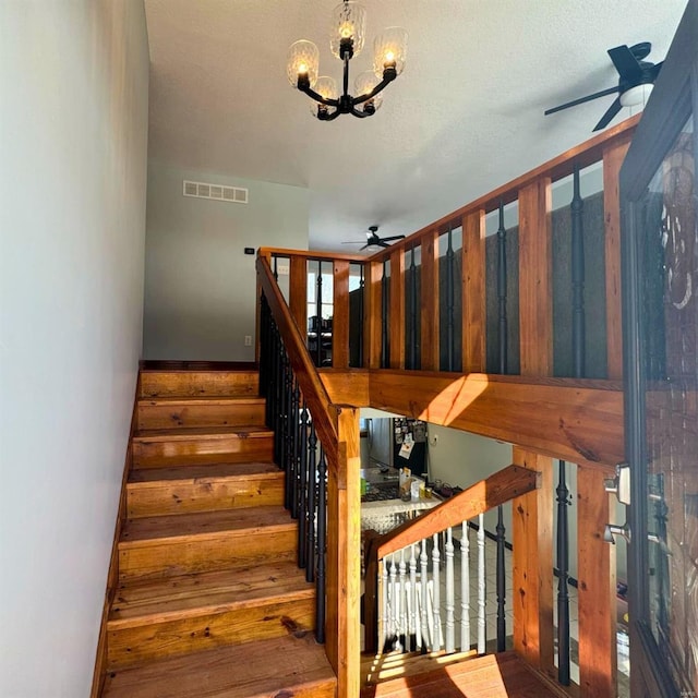 staircase featuring visible vents and ceiling fan with notable chandelier