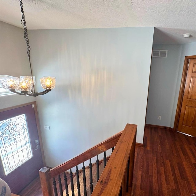 foyer entrance featuring baseboards, visible vents, dark wood-style flooring, a textured ceiling, and a notable chandelier