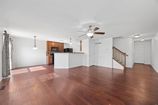 unfurnished living room with visible vents, dark wood-type flooring, ceiling fan, baseboards, and stairs