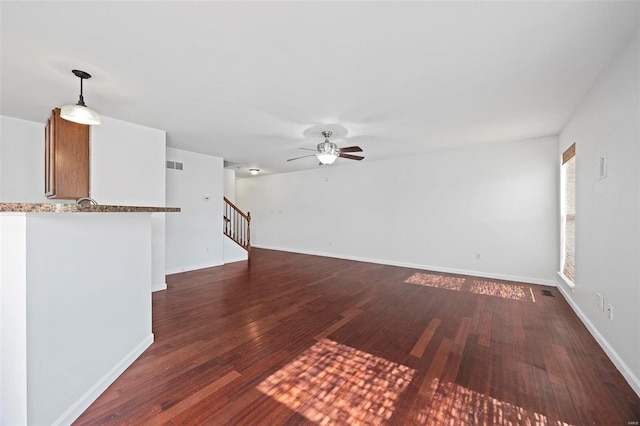 unfurnished living room featuring baseboards, visible vents, a ceiling fan, stairway, and wood finished floors